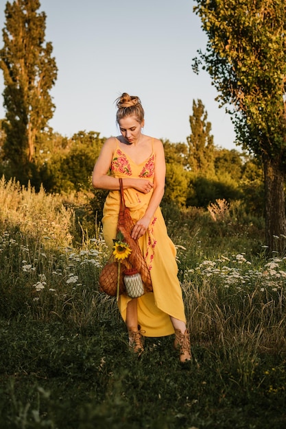 A woman in a flowing bohemian SHEIN dress with a floral print, walking through a field of wildflowers during a golden hour wedding photoshoot, showcasing the dress in a natural and romantic setting.