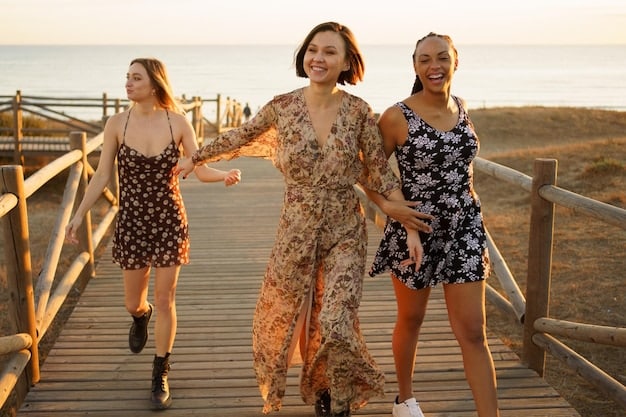 A group of friends laughing and walking along the beach at sunset. They are all wearing different SHEIN summer dresses in pastel colors and bohemian prints.
