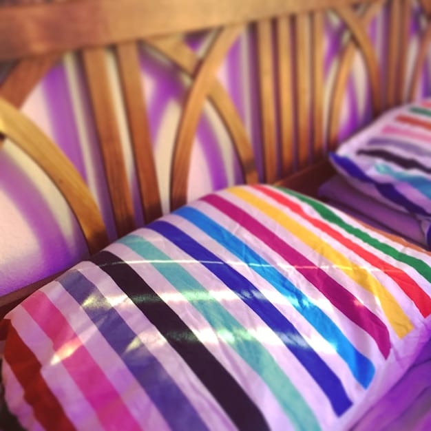 A close-up of a balcony decorated with colorful cushions, a soft blanket, and string lights from SHEIN, highlighting the textures and patterns.