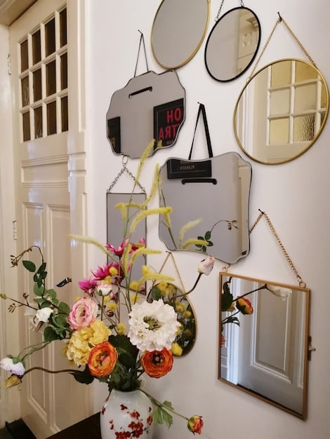 A close-up shot of various SHEIN decorative mirrors hanging on a wall, showcasing different shapes, sizes, and frame designs. The arrangement creates a gallery wall effect.